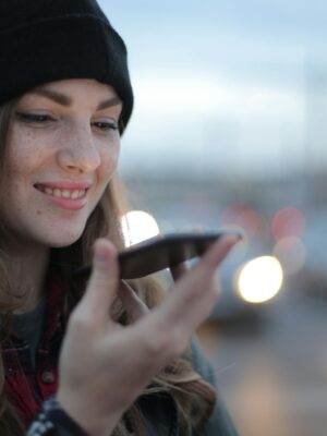 Joyful young woman phoning on street in evening