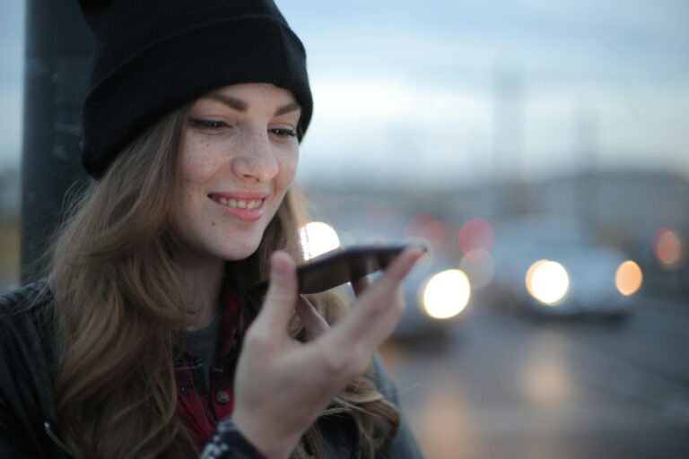 Joyful young woman phoning on street in evening